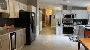 A modern kitchen with white cabinetry, a black refrigerator, a built-in oven, and a microwave. - Florida Woodland Retreat-Nature Coast (Brooksville)