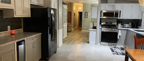 Eine moderne Küche mit weißen Schränken, einem schwarzen Kühlschrank, einem eingebauten Backofen und einer Mikrowelle.
