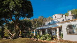 A white building with a circular tower and a large tree in front. - Exceptional private villa with sea view & heated pool (Mijas)
