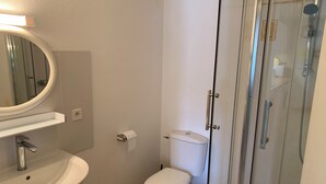 Une salle de bain équipée d’un lavabo, de toilettes et d’une douche à parois de verre.