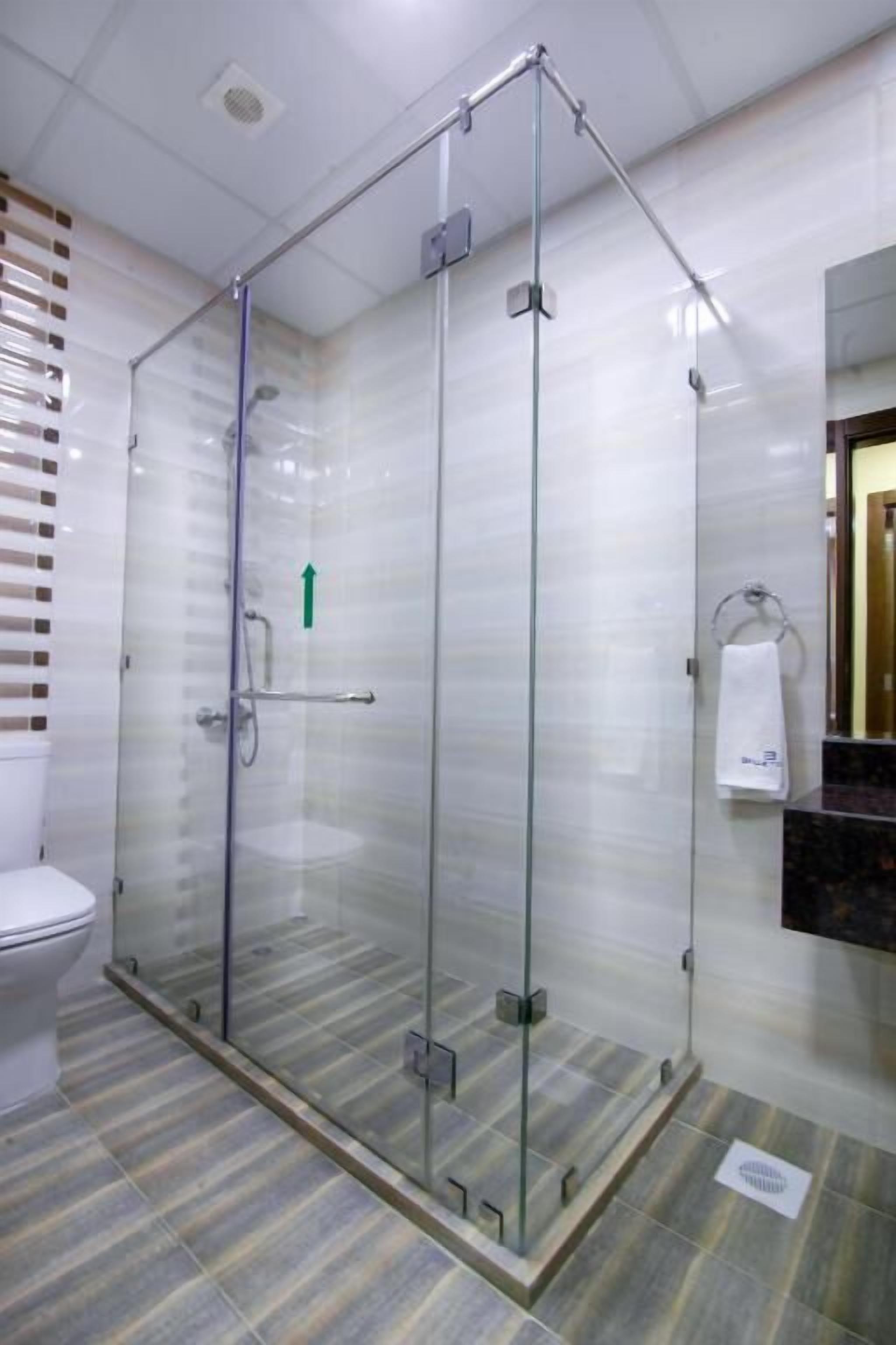 Et moderne badeværelse med bruseniche, toilet og håndvask.
