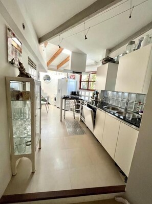 Uma cozinha moderna com armários brancos, bancada preta e uma vitrine de vidro.