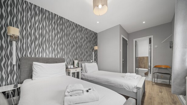 A hotel room with two beds, a bathroom, and a seating area. - Queensferry guest house (Dunfermline)