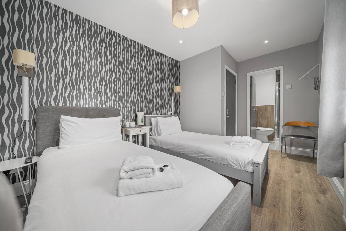 A hotel room with two beds, a bathroom, and a seating area.