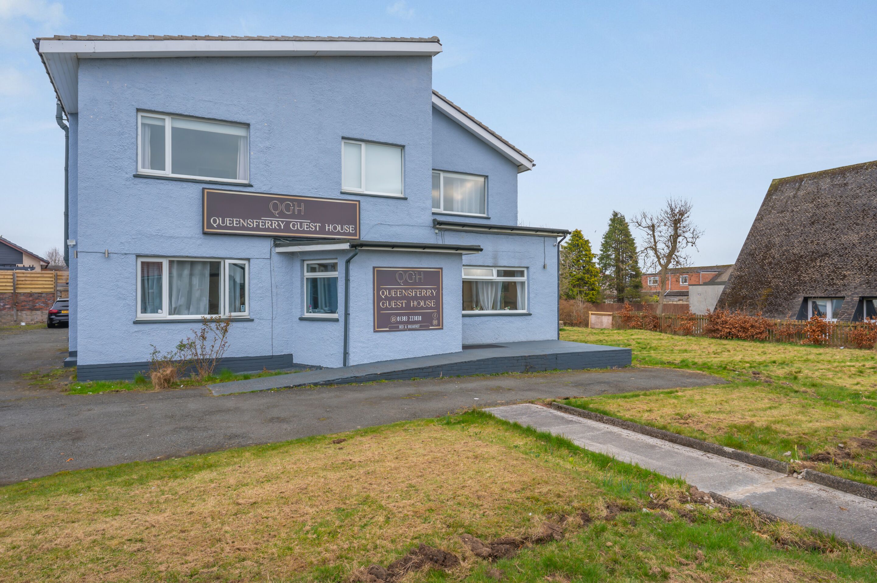 Un edificio de dos pisos con letreros que dicen "Queensferry Guest House".