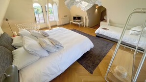 Un dormitorio moderno con una cama grande, una cama más pequeña, una litera, un escritorio y una silla.