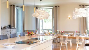 Una cocina moderna con una isla central, armarios blancos e iluminación colgante.
