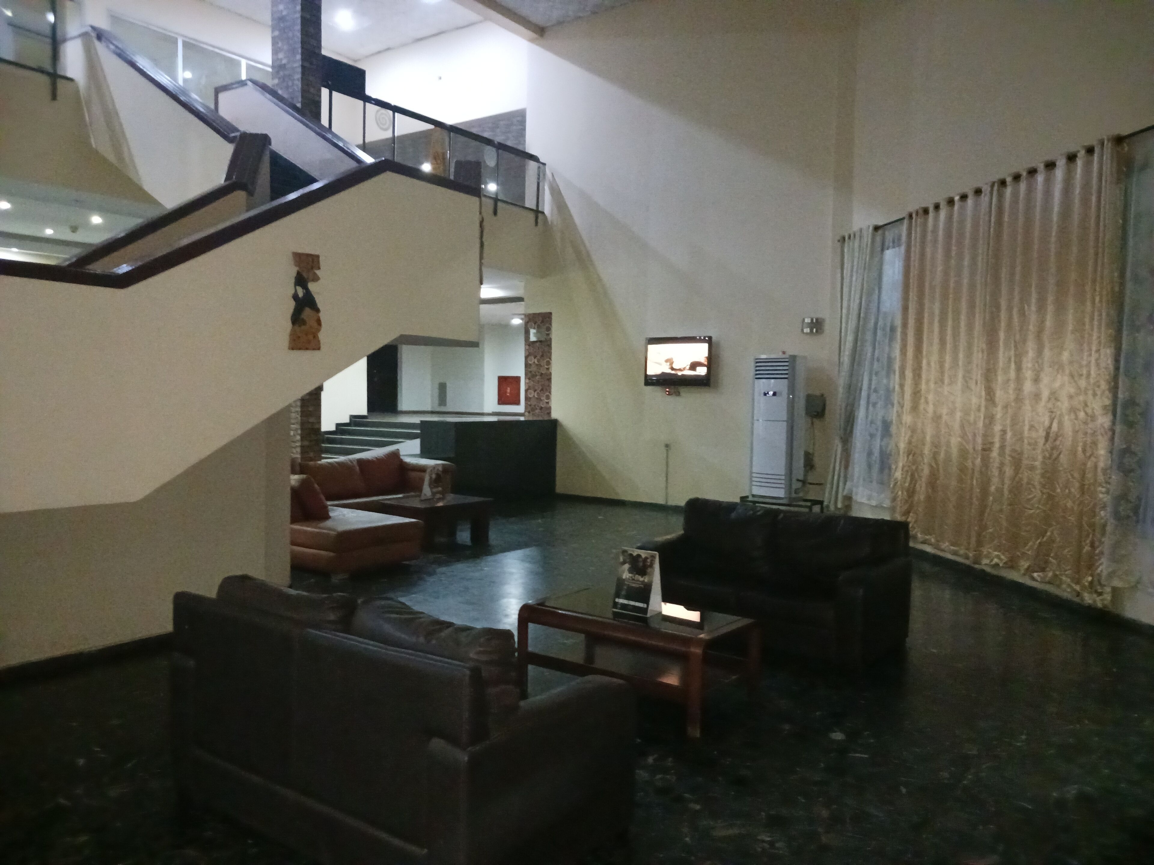 A spacious lobby with a staircase, leather sofas, a coffee table, and a television.
