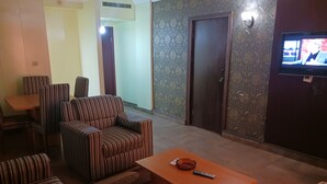 Un salón con sofás a rayas, una mesa de centro de madera y un televisor en la pared.