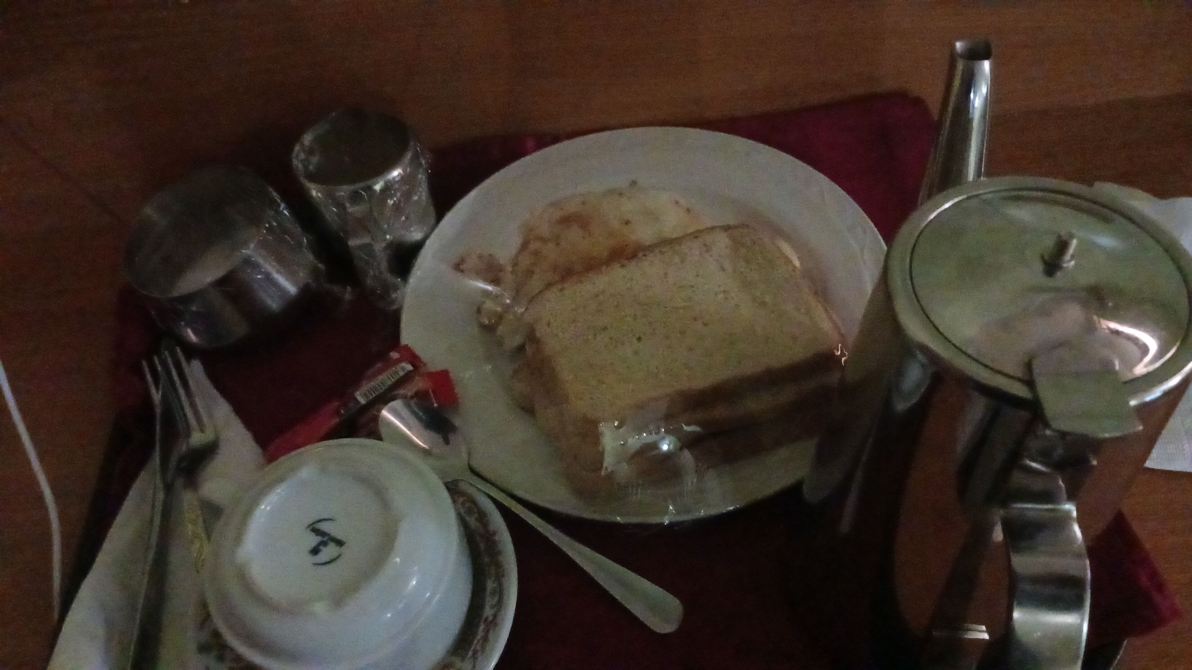 A table with a plate of food, a cup, a spoon, a fork, and a small bowl.