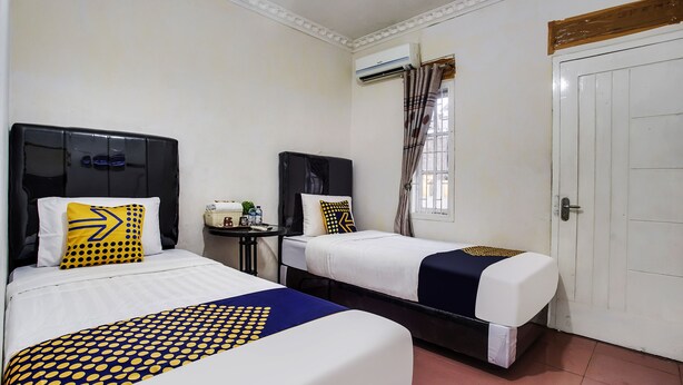 Een hotelkamer met twee bedden, een klein tafeltje met een mand en een deur.