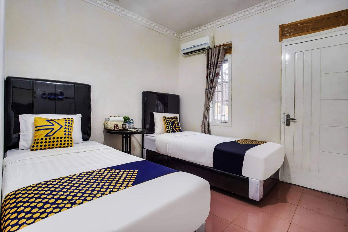 Une chambre d’hôtel avec deux lits, une petite table et un panier, ainsi qu’une porte.