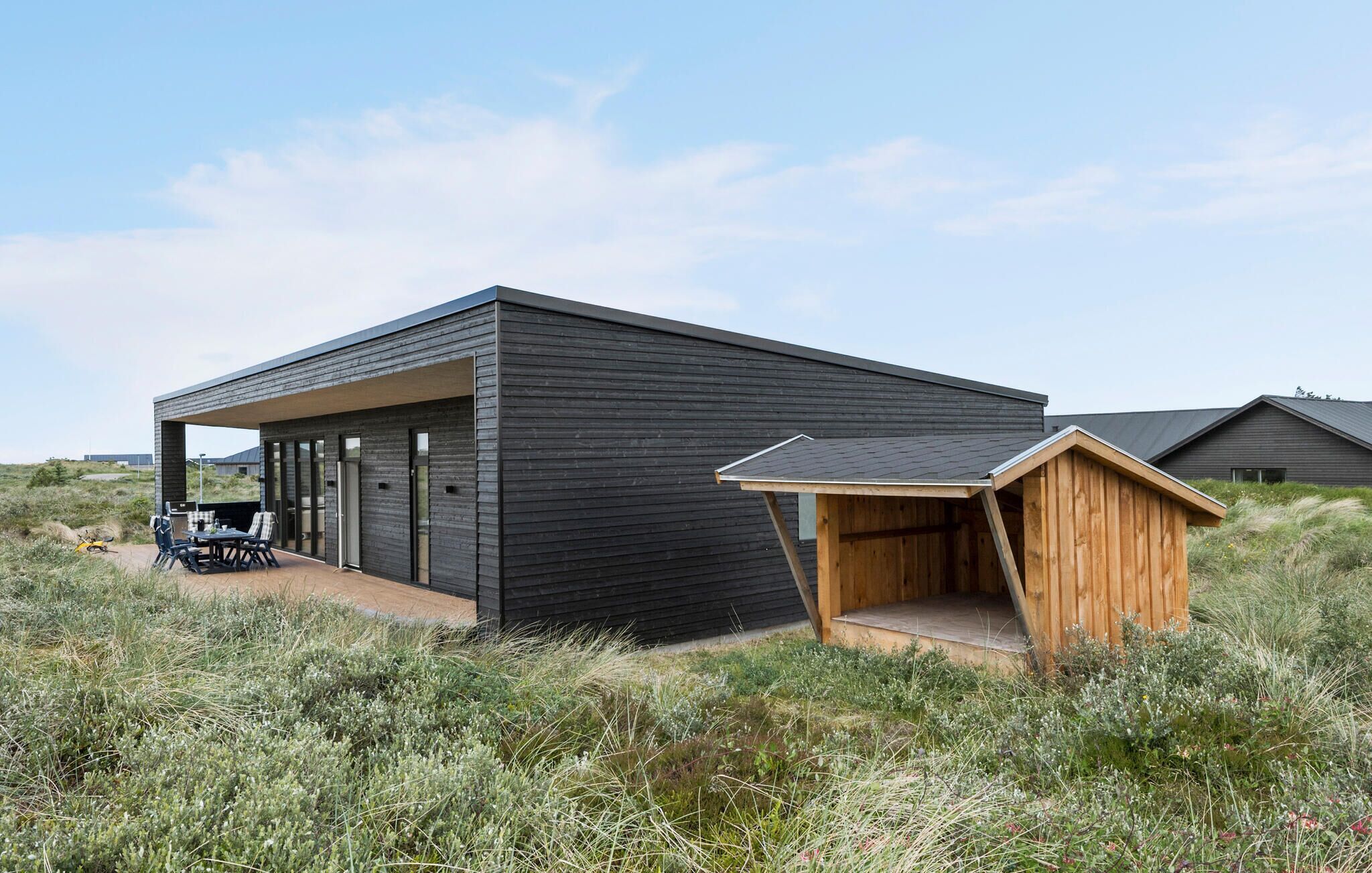 A modern building with a covered outdoor seating area and a wooden structure.