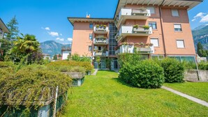 A multi-story building with balconies, a central staircase, and a surrounding green lawn. - Domus Raffaella (Arco)