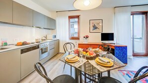 A modern kitchen with a dining area, a television, and a view of the outdoors. - Domus Raffaella (Arco)