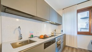 A modern kitchen with a stainless steel sink, a dishwasher, an oven, and a microwave. - Domus Raffaella (Arco)