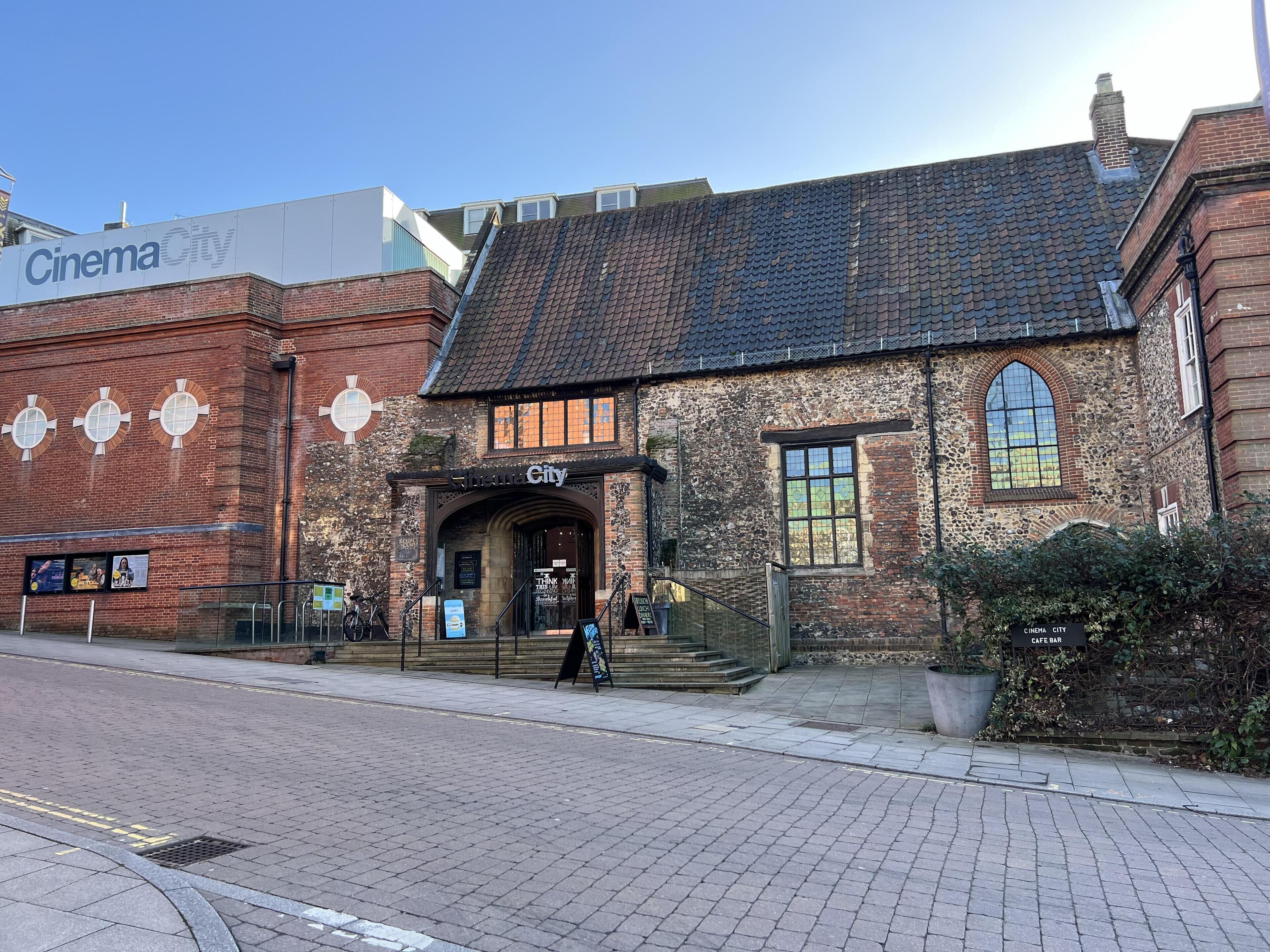Un edificio histórico con cine y café bar, que presenta fachada de ladrillo y entrada abovedada.