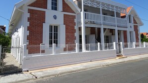 A two-story house with a balcony, white railings, and a brick facade. - 23   (Soulac-sur-Mer)