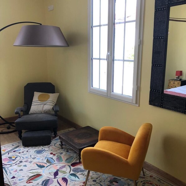 A room with a black armchair, a yellow armchair, a patterned rug, a lamp, and a window with a view. - 23 (Soulac-sur-Mer)