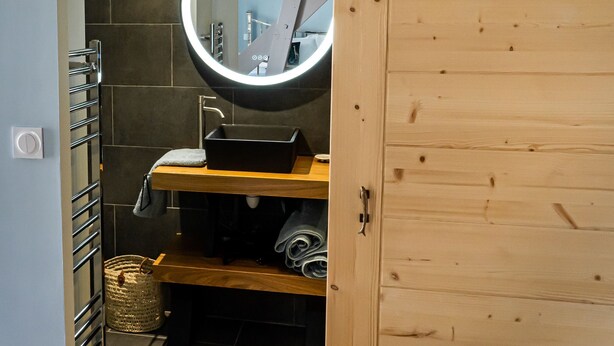 A bathroom with a wooden vanity, a round mirror, and a towel rack. - 23   (Soulac-sur-Mer)