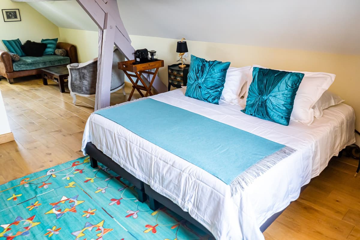 A bedroom with a bed, a desk, a chair, and a sofa.