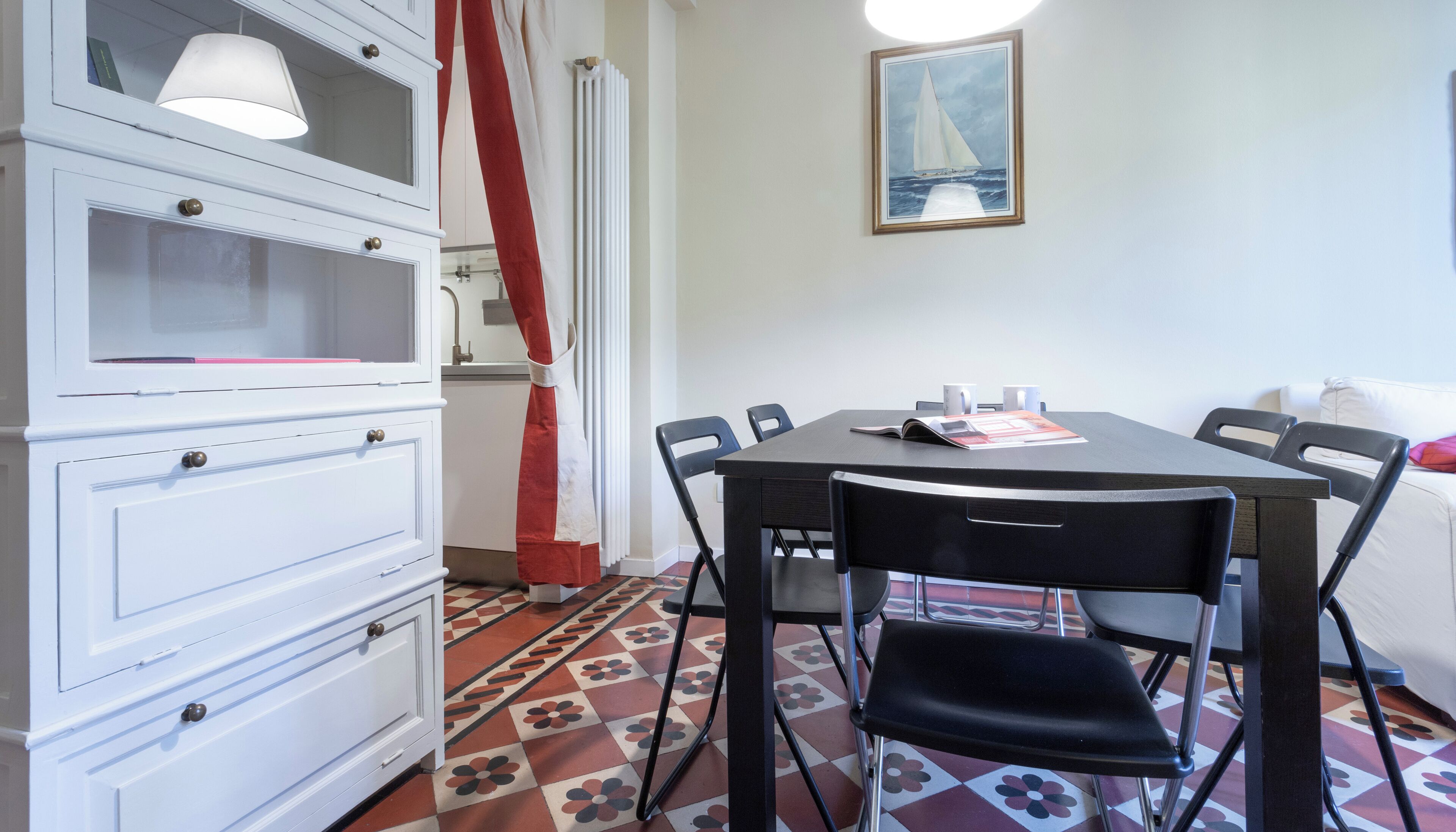 A dining area with a table, chairs, and a white cabinet with drawers.