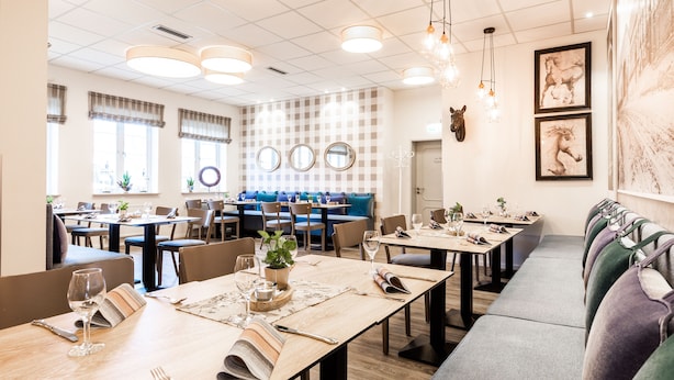 En restaurant med flere spiseborde, bænke og hængende lys.