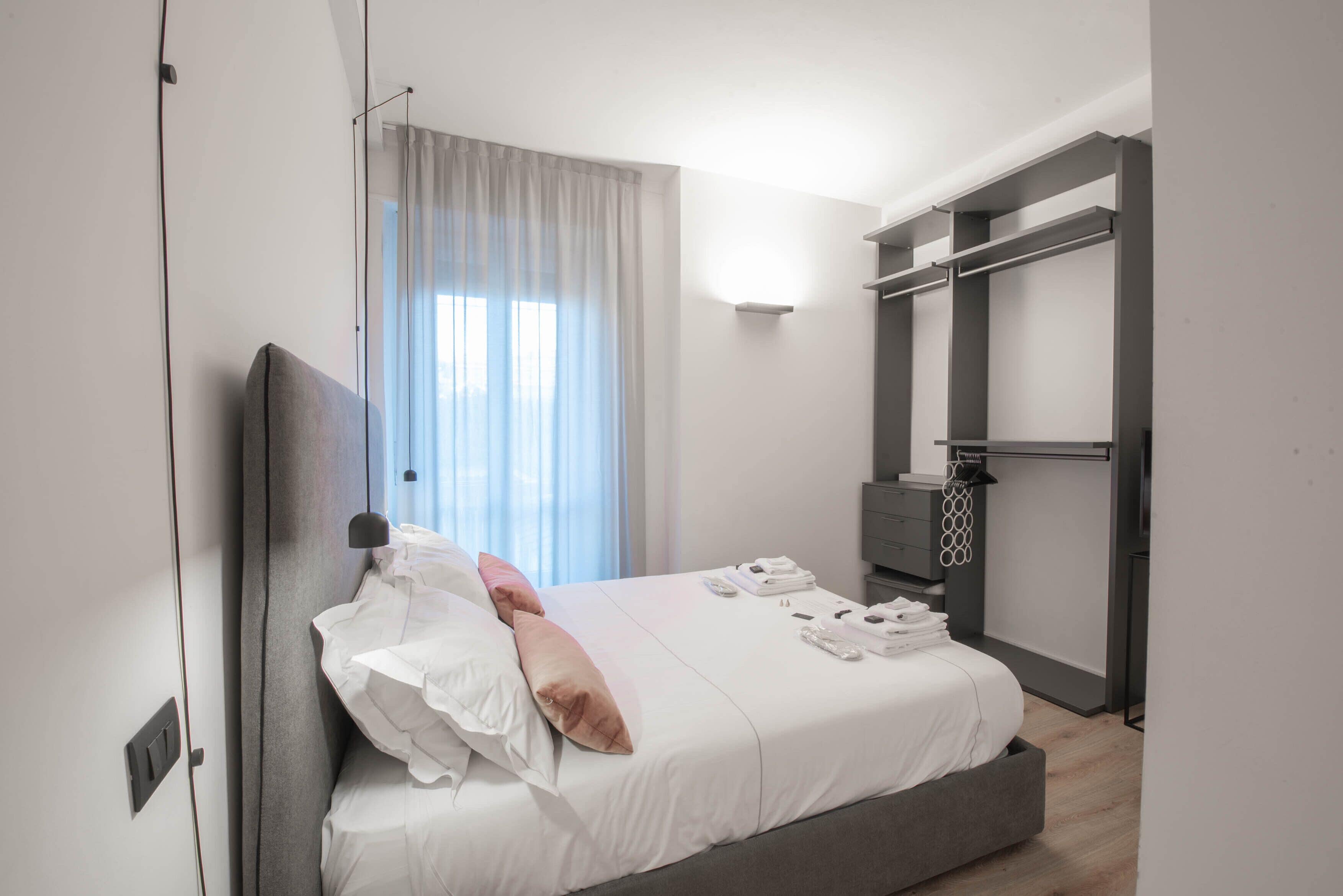 A modern bedroom with a bed, bedside tables, a wardrobe, and a window with curtains.