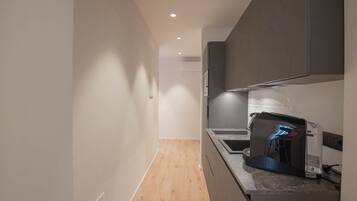 A modern kitchen with a built-in oven and microwave, wooden flooring, and recessed ceiling lighting.