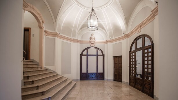 A grand hallway with a marble staircase, a large arched doorway, and a hanging lantern. - SAN CARLO SUITE TORINO (Turin)