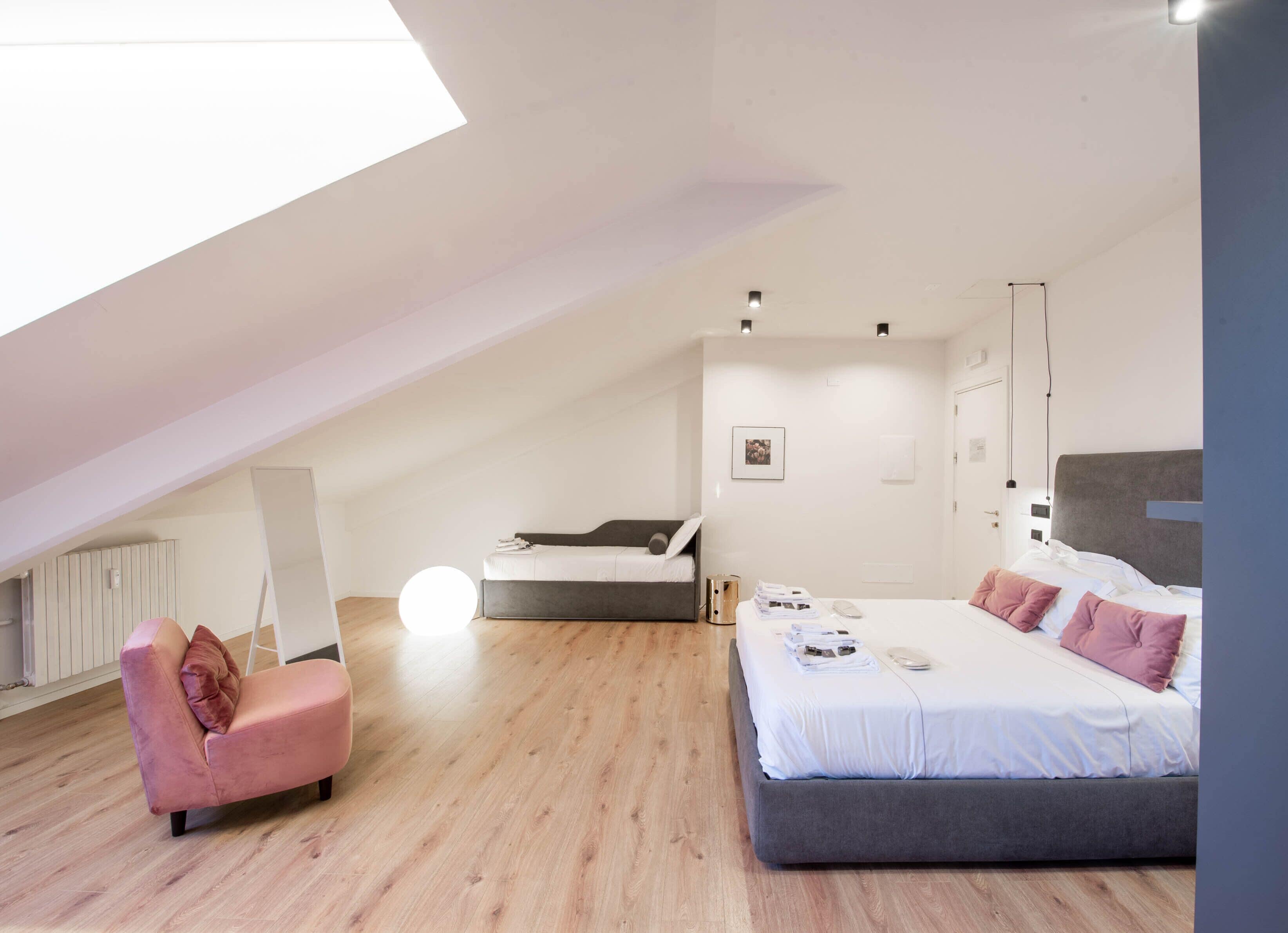 Un dormitorio moderno con una cama grande, un sofá y un tragaluz.