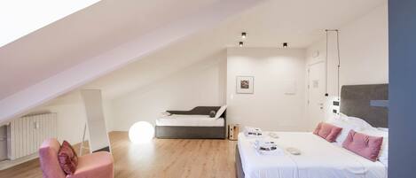 Ein modernes Schlafzimmer mit einem großen Bett, einer Couch und einem Oberlicht.