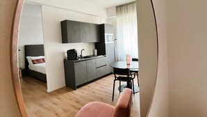 A modern apartment with a round mirror reflecting a living area, a kitchen, and a dining space. - SAN CARLO SUITE TORINO (Turin)