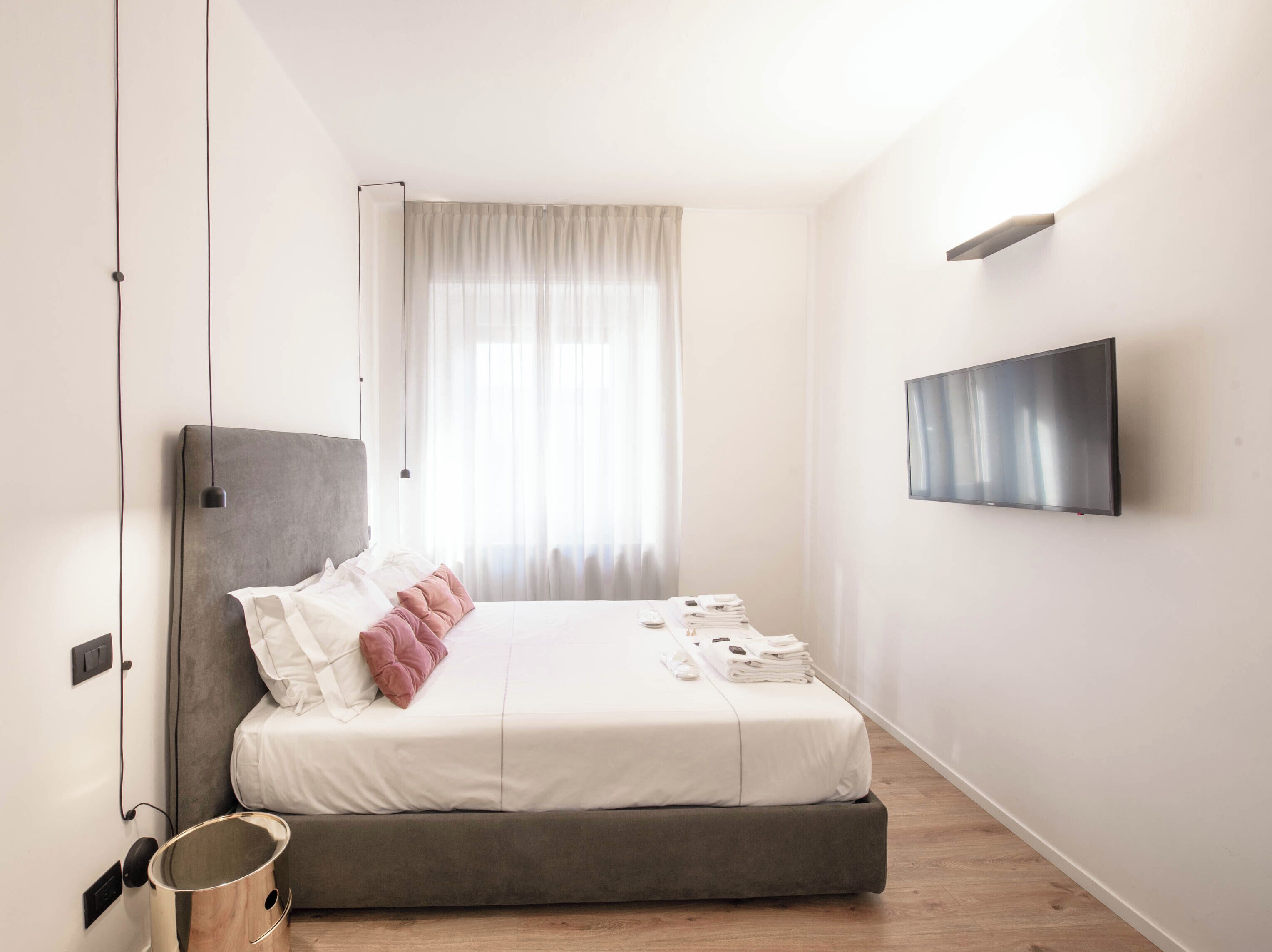 Una camera da letto moderna con un letto, una TV e una finestra con tende.