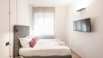 Una camera da letto moderna con un letto, una TV e una finestra con tende.