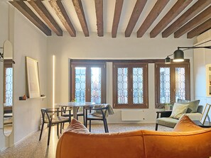 Relax in this inviting living space with a dining area, comfortable seating, and large windows offering views of the outside.