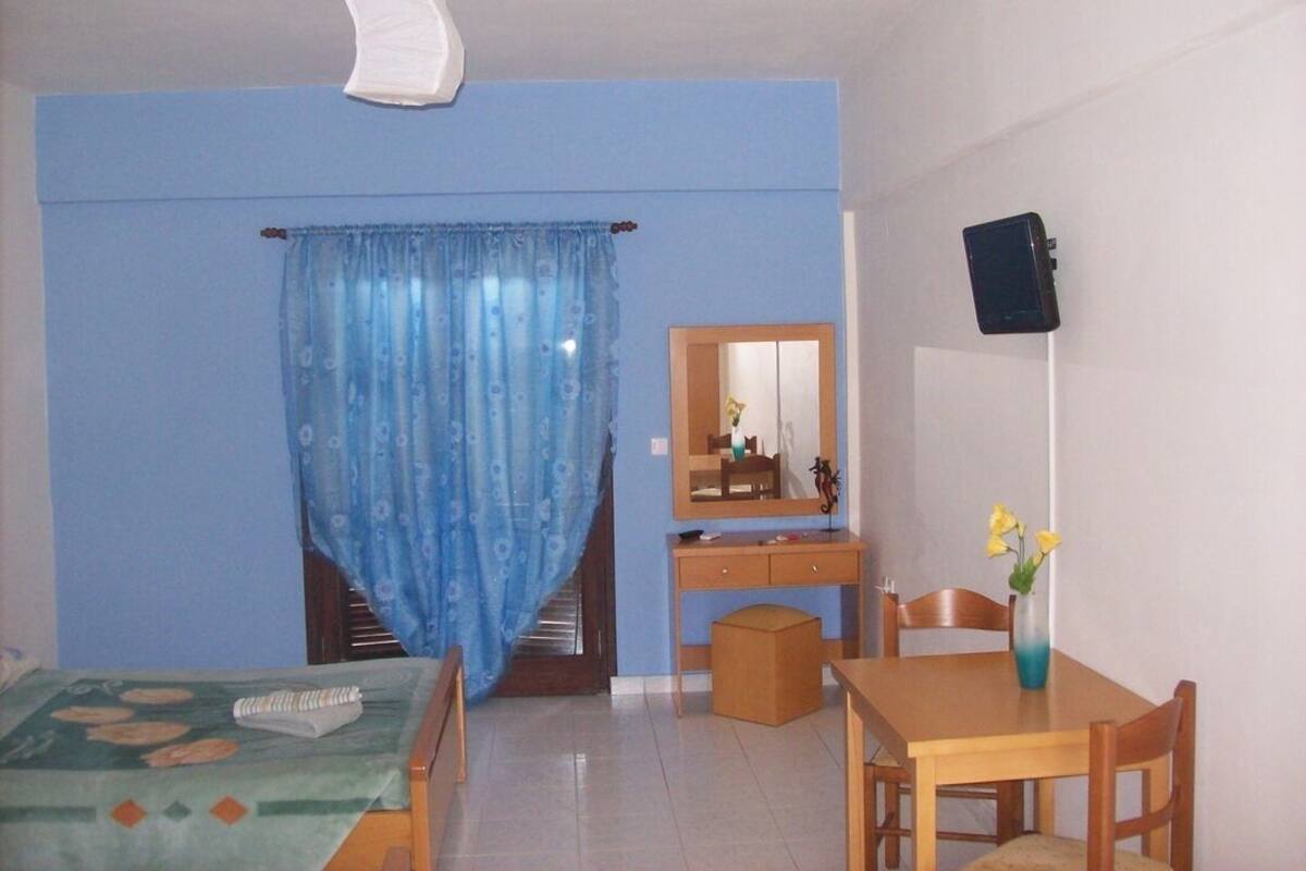 Una habitación con una cama, un escritorio, una silla, una mesita y un espejo.