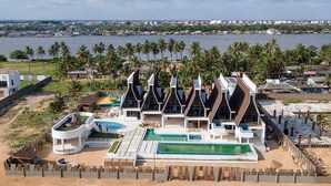 A modern resort with a pool, multiple villas, and a view of the water and city skyline.