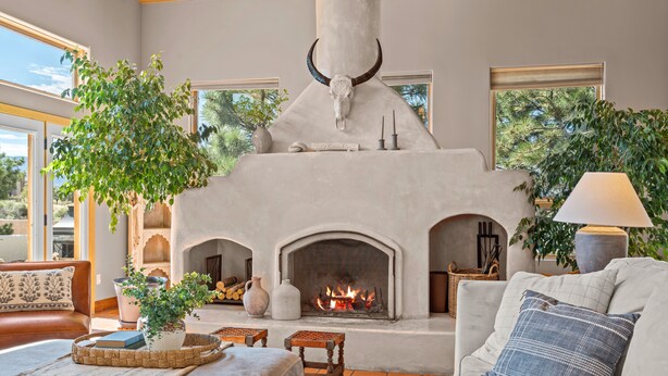 A cozy living room with a fireplace, a sofa, a coffee table, and a potted plant. - Location, Location!! Unforgettable Sunsets-Balloon Fiesta dream home! (Albuquerque)