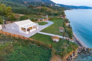 A modern house with a large patio, a swimming pool, and a view of the sea.