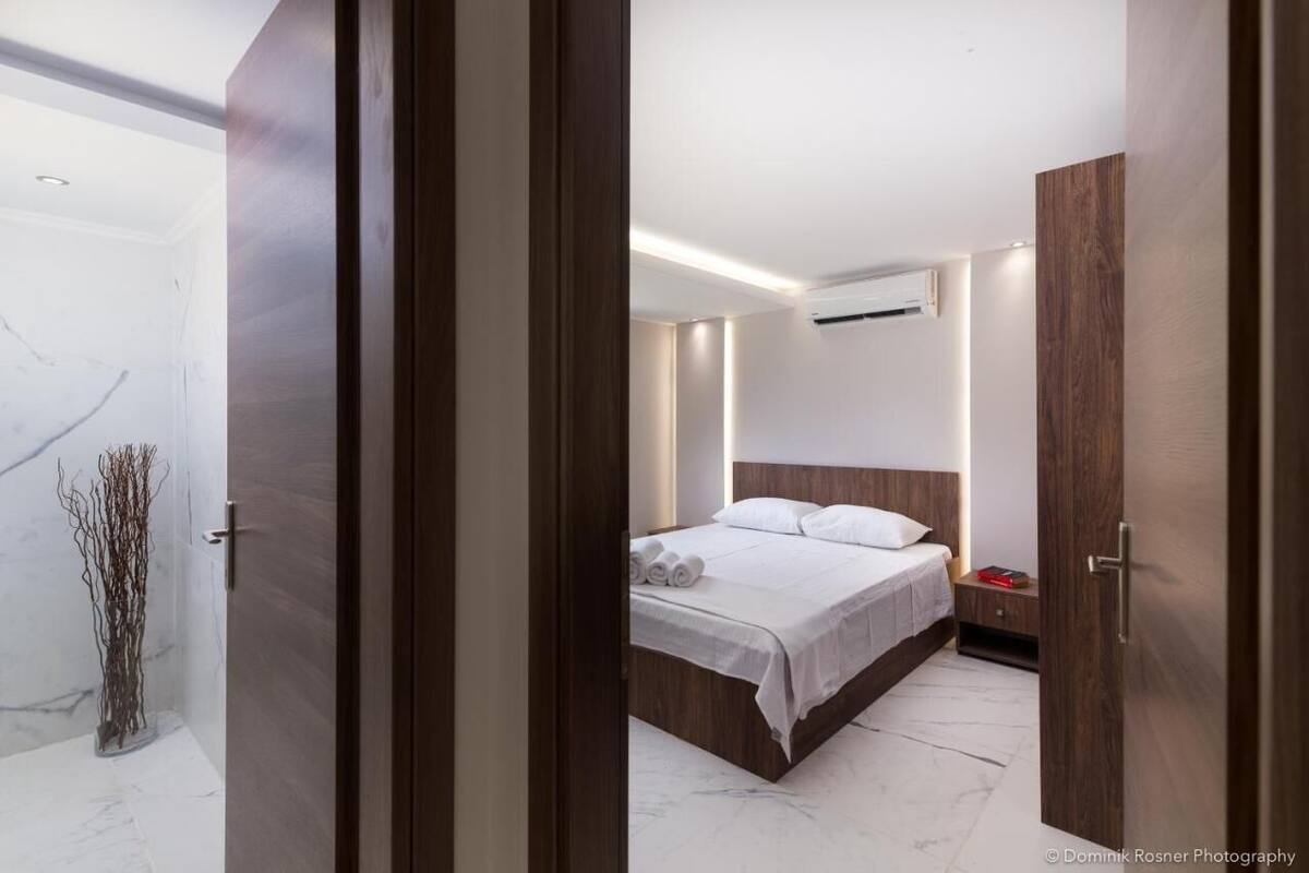 A modern bedroom with a wooden bed, a nightstand, and a marble floor.