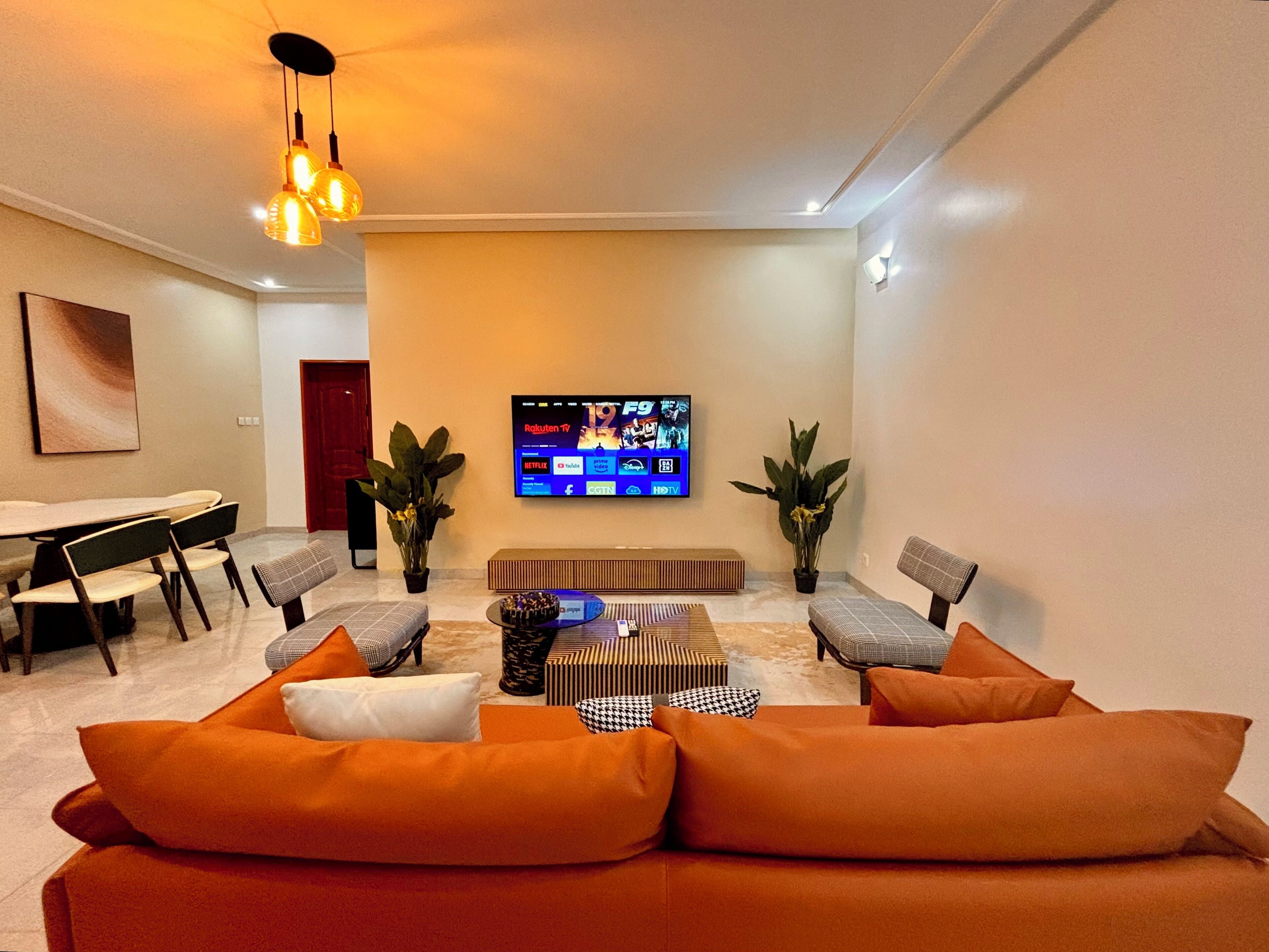 A modern living room with a sofa, chairs, a coffee table, and a flat-screen TV mounted on the wall.