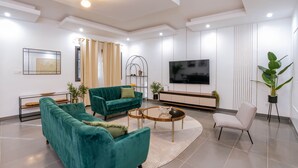 Un salon moderne avec un canapé d’angle, une table basse, un téléviseur et une plante en pot.