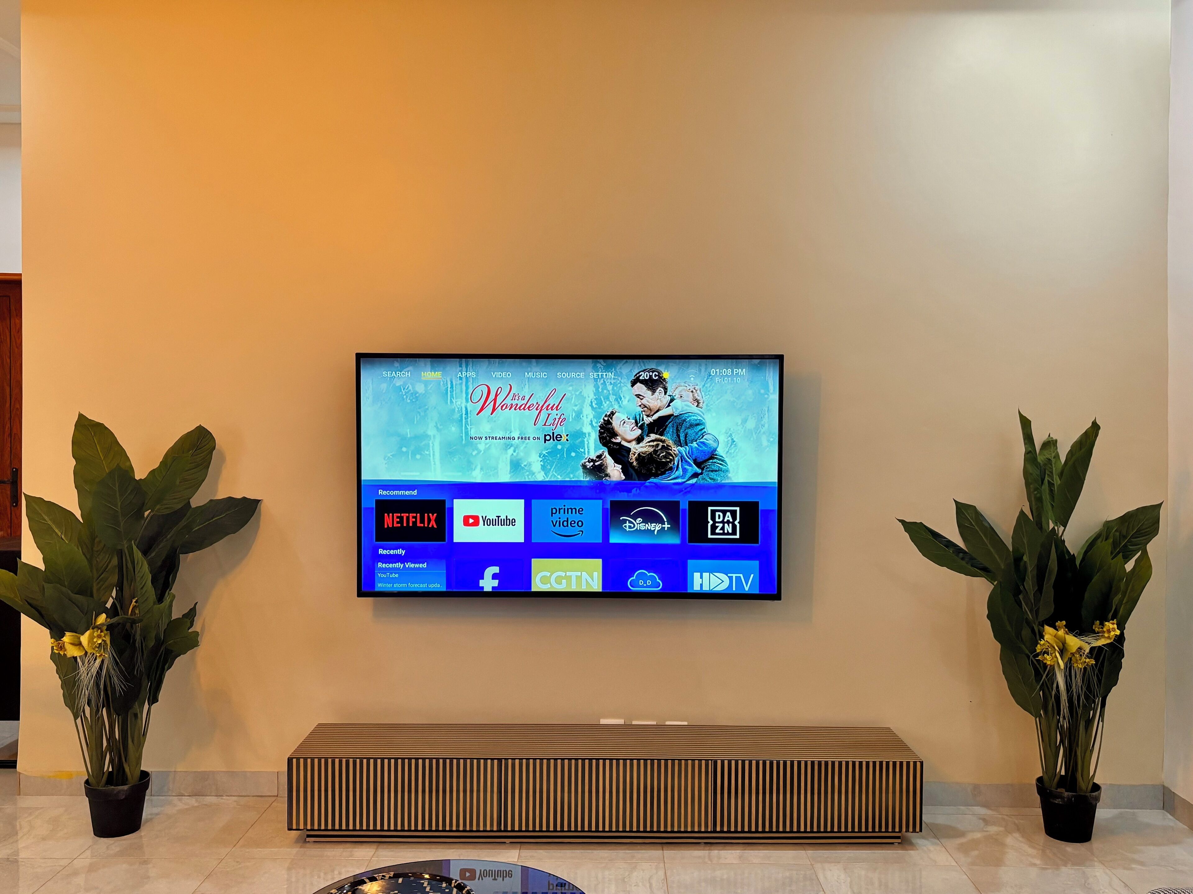 A flat-screen TV mounted on a wall displaying a streaming service interface with a winter-themed background.
