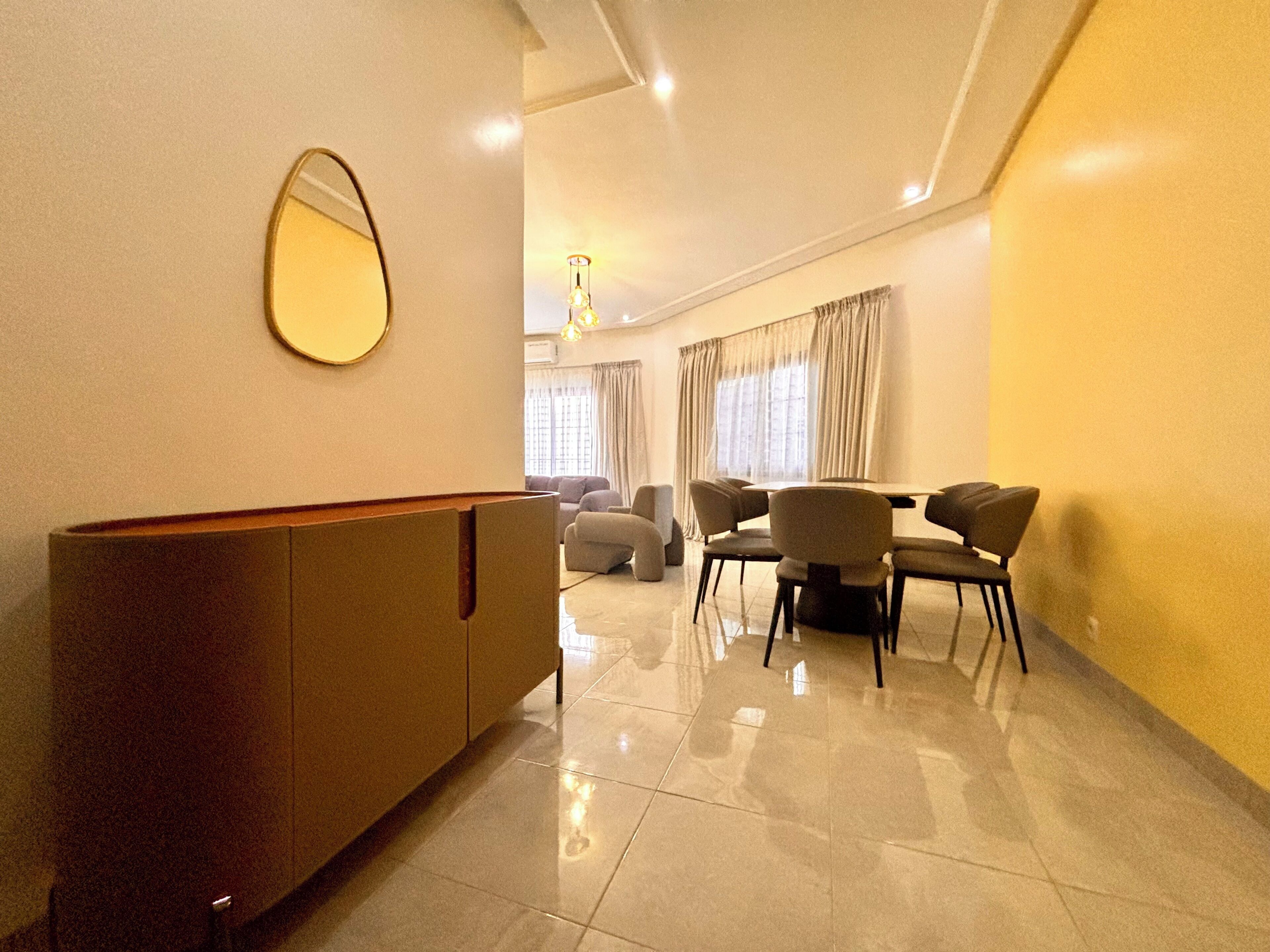 A modern living room with a dining area, a large mirror, and a sofa.