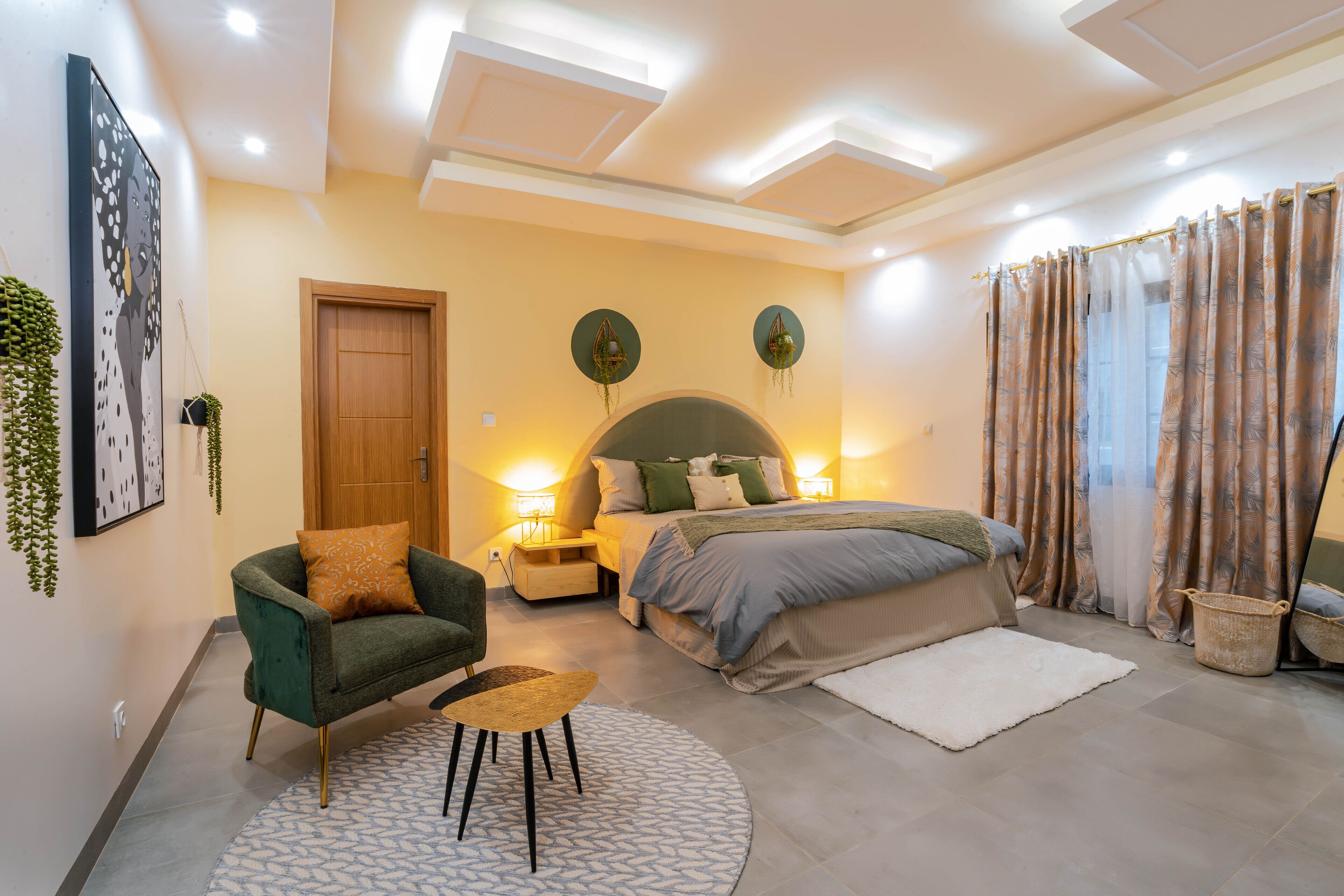 A modern bedroom with a bed, a chair, a small table, and a nightstand.