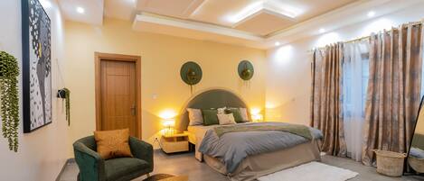 A modern bedroom with a bed, a chair, a small table, and a nightstand.