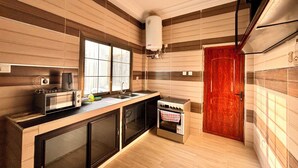 Une cuisine avec des lambris en bois, une cuisinière, un évier et une fenêtre.