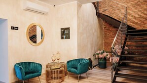 A modern interior with a staircase, two teal armchairs, a round mirror, and a small table with decorative items. - Casa Gallo-Adults Only Sibiu (Sibiu)