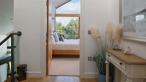Une chambre à coucher comprenant un lit, une table de chevet, une commode et une fenêtre donnant sur un paysage verdoyant.